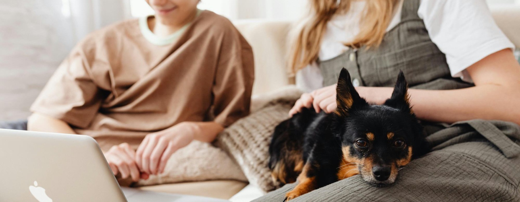 a mother and son looking at a laptop petting a dog